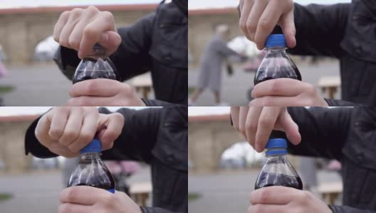 一个男人的手拧开苏打水瓶的顶部在街头咖啡馆的特写。在4 k拍摄高清在线视频素材下载