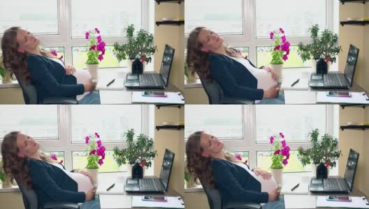 放松的孕妇在她的椅子上摆动工作地点在办公室高清在线视频素材下载