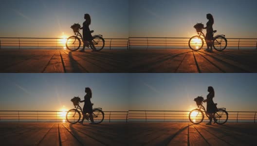 年轻女子的剪影穿着复古自行车和鲜花走在海边的木堤岸在日出或日落。浪漫的旅行概念。美丽的景色高清在线视频素材下载