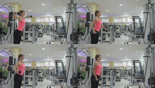 Beautiful young woman doing exercises with dumbbells at biceps.高清在线视频素材下载