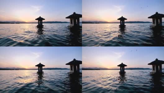 中国杭州西湖美丽的夕阳景观，橘色的黄昏天空和宁静的水与湖中的传统亭台楼阁，闪烁的涟漪，4k电影，慢镜头。高清在线视频素材下载