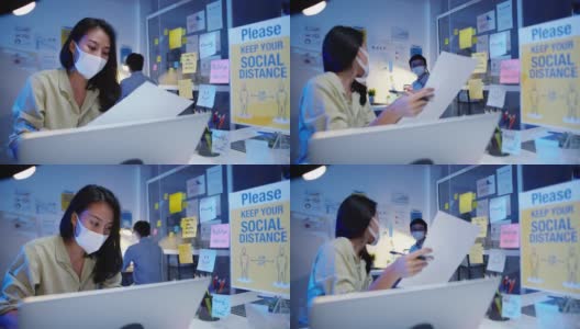 在新常态下，快乐亚洲女企业家戴着防毒面具，一边进行社交距离，一边讨论商业头脑风暴会议，晚上上班一起分享数据高清在线视频素材下载