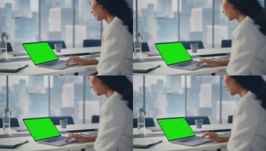 成功的亚洲女商人坐在办公室的绿色屏幕色度键笔记本电脑上工作。为电子商务项目做研究的优秀高层管理者。在肩膀上高清在线视频素材下载
