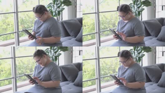 快乐的自闭症女孩在客厅里用平板电脑高清在线视频素材下载