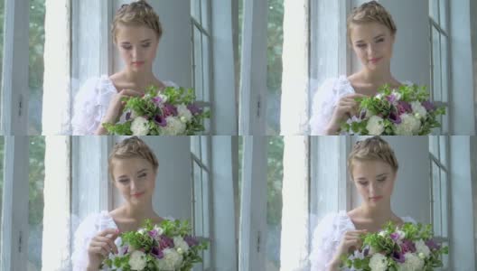 美丽的女孩，穿着复古的白色连衣裙，坐在窗台上触摸鲜花，微笑，慢镜头高清在线视频素材下载