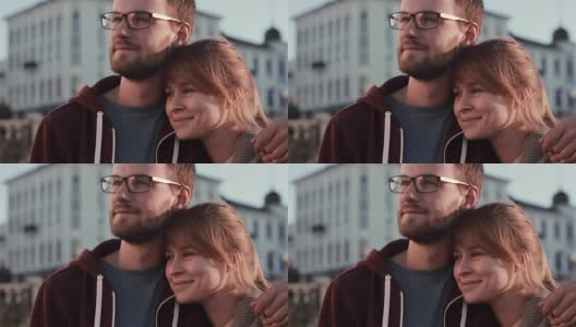 这是一对年轻美丽的夫妇站在市中心向一边看的肖像。日落时分，快乐的男人和女人拥抱在一起高清在线视频素材下载