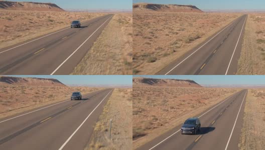 空中特写:一辆黑色SUV行驶在空旷的道路上，穿过广阔的沙漠山谷高清在线视频素材下载