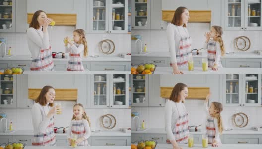 快乐的小女孩和她的妈妈在厨房享用新鲜可口的冰沙，并互相击掌庆祝高清在线视频素材下载