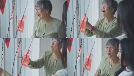中国新年老女人和她的女儿装饰房子客厅用柳树和红包昂炮装饰准备家庭团聚高清在线视频素材下载