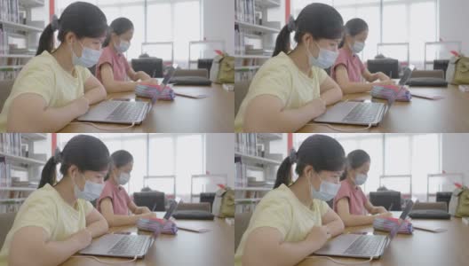 新常态亚洲女孩在图书馆网上学习戴口罩防止冠状病毒covid - 19的概念技术教育高清在线视频素材下载