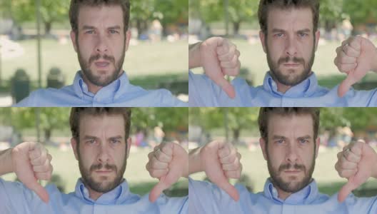 近距离的肖像，有吸引力的男人在30岁给两个拇指向下高清在线视频素材下载