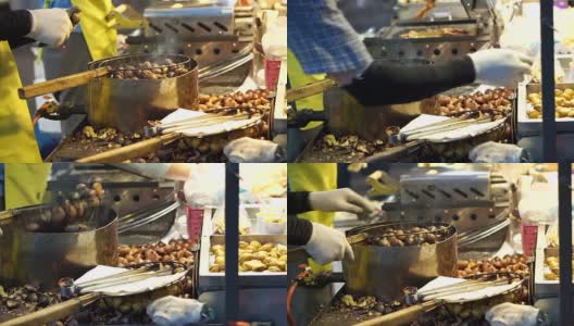 小贩在街头小吃摊上烤鱿鱼和剥烤栗子。亚洲秋食高清在线视频素材下载
