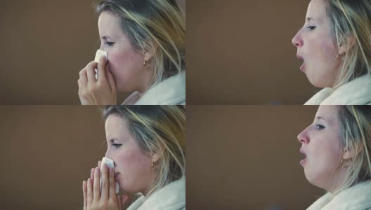 慢镜头:一个女孩在一个家庭睡衣打喷嚏和擦他的鼻子与手帕在沙发上。高清在线视频素材下载