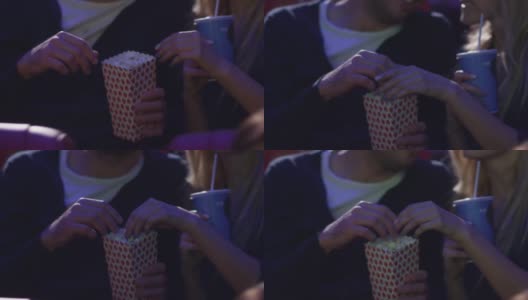 一对年轻的浪漫情侣手牵着手在电影院看电影。高清在线视频素材下载