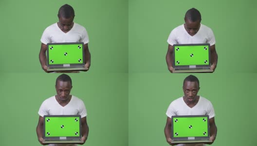 年轻的非洲男子在展示笔记本电脑时看起来很震惊高清在线视频素材下载