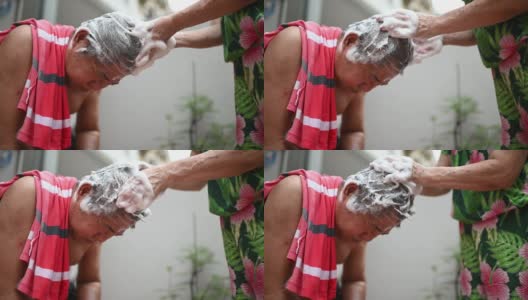 亚洲华人老年妇女洗她的丈夫的头发，洗头在前院当没有水供应高清在线视频素材下载