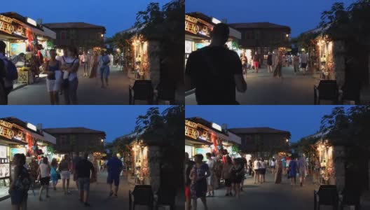 时间流逝晚上，人们在城市里散步。快速拍摄游客在老城区的商店和纪念品之间。在夏天炎热的傍晚散步。高清在线视频素材下载