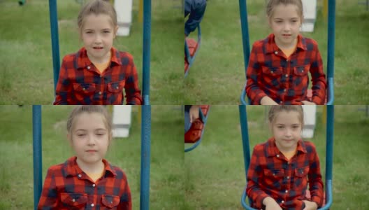 画一个小女孩穿着红衬衫在秋千上。年轻快乐的孩子用灰色的眼睛看着孩子们玩耍。好奇的孩子靠近高清在线视频素材下载