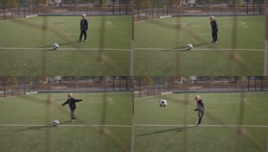 一个小男孩足球运动员用足球击中了球门。高清在线视频素材下载