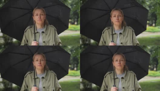 一个女人在雨中站在伞下的脸部特写高清在线视频素材下载