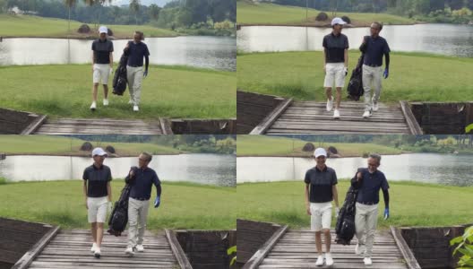 一名亚洲华人男子带着十几岁的儿子往高尔夫球场走去，手里拿着高尔夫球袋看风景高清在线视频素材下载