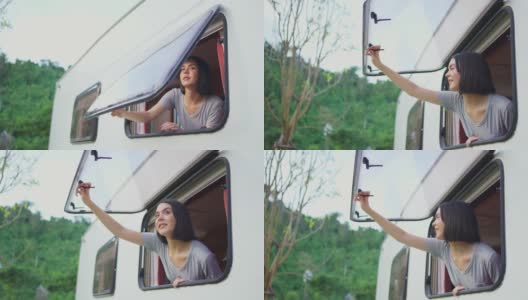 亚洲年轻女孩感觉放松在露营车打开窗户在早上与幸福和微笑的假期。女旅人望着窗外的自然风光，美丽的山。高清在线视频素材下载