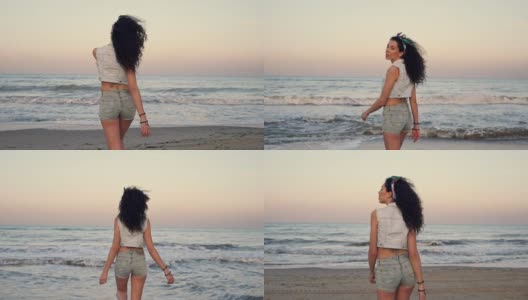 快乐漂亮的卷发女人在海滩上散步的后视图高清在线视频素材下载
