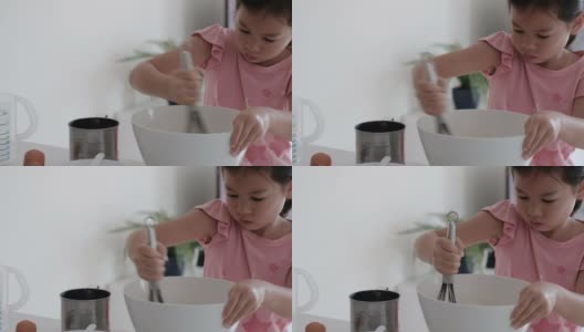 年轻的混合亚洲女孩帮助在家里做华夫饼的早餐，家庭教育，蒙特梭利教育的概念高清在线视频素材下载