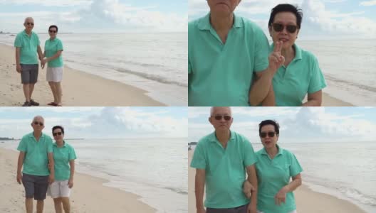 一对亚洲老年夫妇在海滩上愉快地散步。手牵着手，互相交谈高清在线视频素材下载