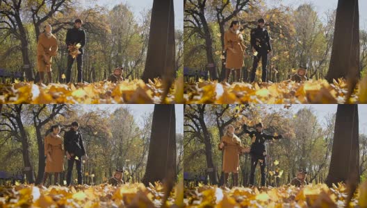 快乐的一家人在公园里玩着秋叶。妈妈和爸爸向空中抛了一圈链子。小孩子看着他们玩得很开心高清在线视频素材下载