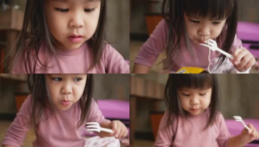 亚洲小女孩有乐趣吃面条在塑料杯在家里。垃圾食品的概念。高清在线视频素材下载