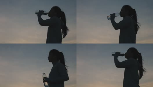 剪影年轻的亚洲女性跑步喝水后，户外日落在山上。高清在线视频素材下载