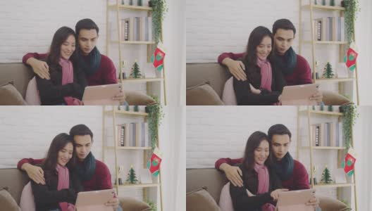 年轻的亚洲夫妇情人视频通话与平板电脑在圣诞节和快乐的新年假期节日在家。圣诞节庆祝活动的概念。4 k慢动作。高清在线视频素材下载