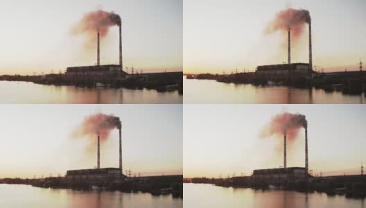 一股股黑色的烟雾释放到大气中。日落时分，工厂排放的有害气体污染了河边的空气。生态灾难。高清在线视频素材下载