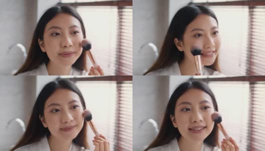 弥补。漂亮的亚洲女人用化妆刷在脸颊上涂腮红高清在线视频素材下载