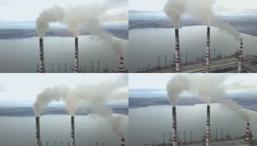 从空中俯瞰高耸的烟囱管和灰色的烟从燃煤电厂。用化石燃料发电。高清在线视频素材下载