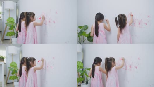 亚洲小女孩喜欢在客厅的白墙上作画。可爱的小朋友们在家里愉快地画画、涂色，享受着节日的创意活动。高清在线视频素材下载