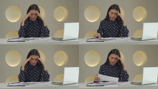一名亚洲女性在办公室用手捂住脸，在办公桌上用笔记本电脑工作后，心情烦躁高清在线视频素材下载