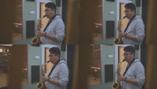 亚洲华人中年男子学习乐器演奏萨克斯在音乐工作室班高清在线视频素材下载