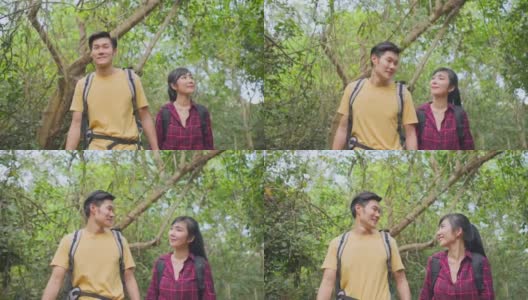 年轻的亚洲男人和女人朋友一起在森林里旅行。情侣们在大自然中感受清新和放松，看着窗外的风景，然后带着幸福和乐趣继续散步。高清在线视频素材下载
