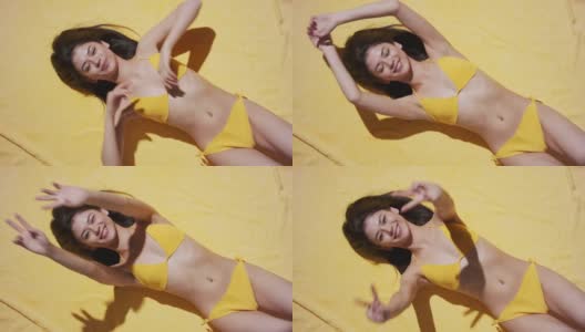 躺在黄色沙滩毯上的女子双手动来动去，显示出平静高清在线视频素材下载