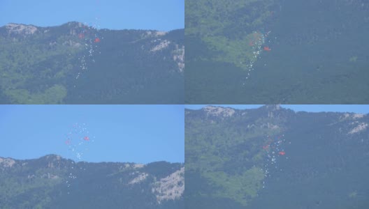 蓝、白、红三种颜色的气球在群山的映衬下升起高清在线视频素材下载