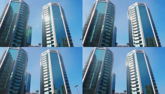 在沙迦现代城市的现代摩天大楼的玻璃幕墙反射阳光高清在线视频素材下载