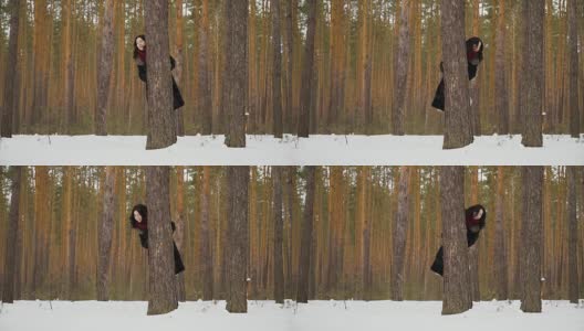 可爱的女人凝视着冬日森林里的树高清在线视频素材下载