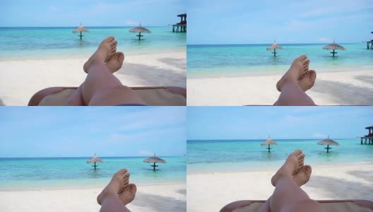 游客光着脚坐在金色沙滩长椅上，指出热带海洋天堂高清在线视频素材下载