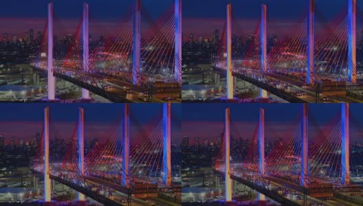 夜深的车流在灯火通明的科修斯科大桥上行驶，远处曼哈顿和布鲁克林的景色映入眼帘。航拍视频与向后平移摄像机运动。高清在线视频素材下载