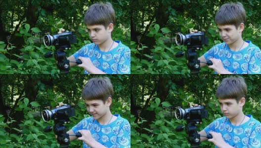 小男孩带着摄像机拍摄关于公园自然背景的影片。高清在线视频素材下载