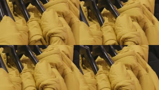 温暖的黄色冬季夹克挂在女装精品店的衣架上高清在线视频素材下载