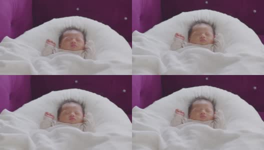 特写快乐的新生儿躺在白色的毯子上睡觉，舒适和安全。可爱的亚洲新生儿在床上睡觉和打盹。新生儿摄影理念高清在线视频素材下载