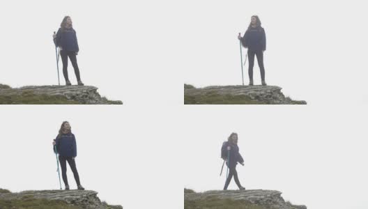 快乐的登山家年轻女子的特写被雾包围站在山顶看远处的风景高清在线视频素材下载